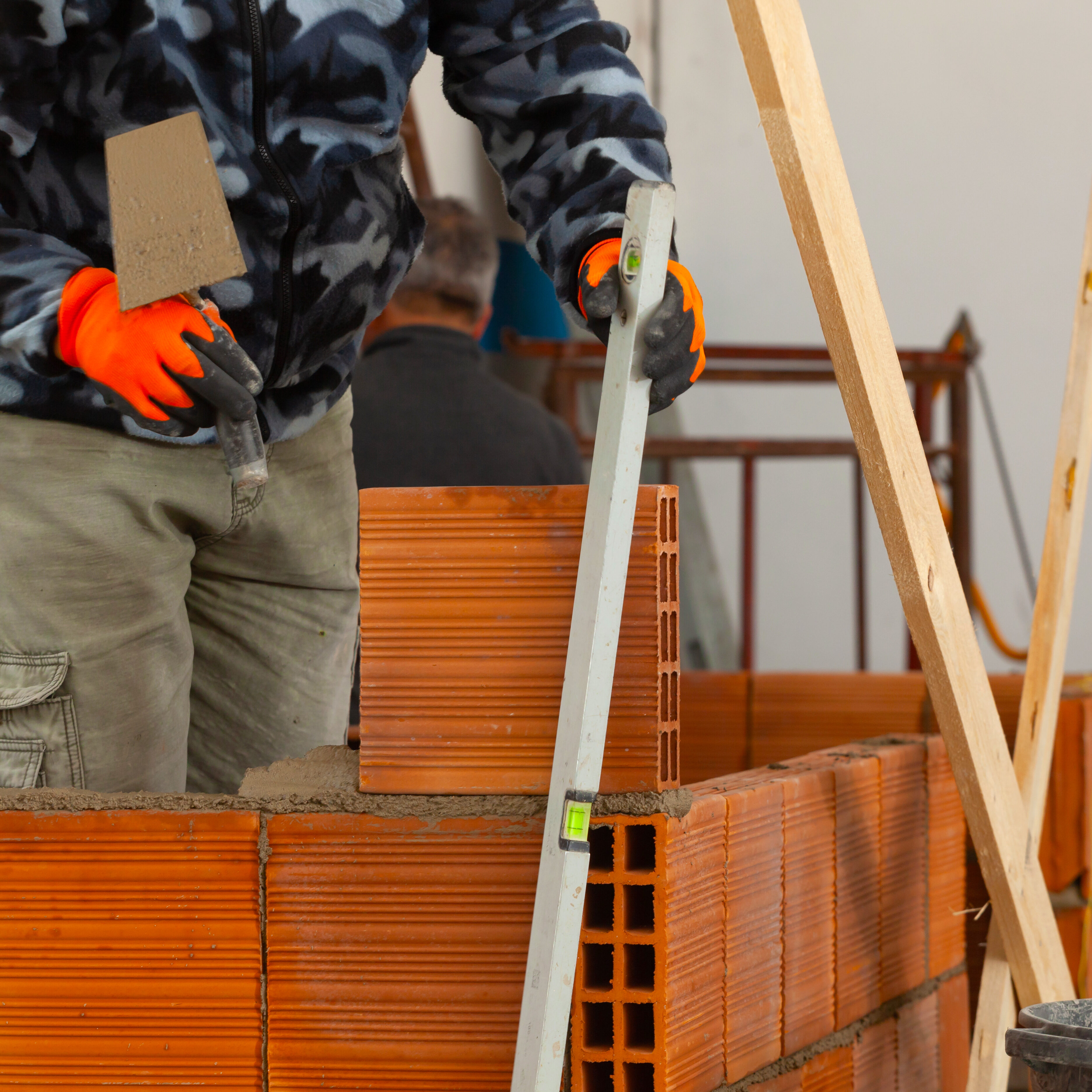 Bricklayer installing brick masonry on interior wall.