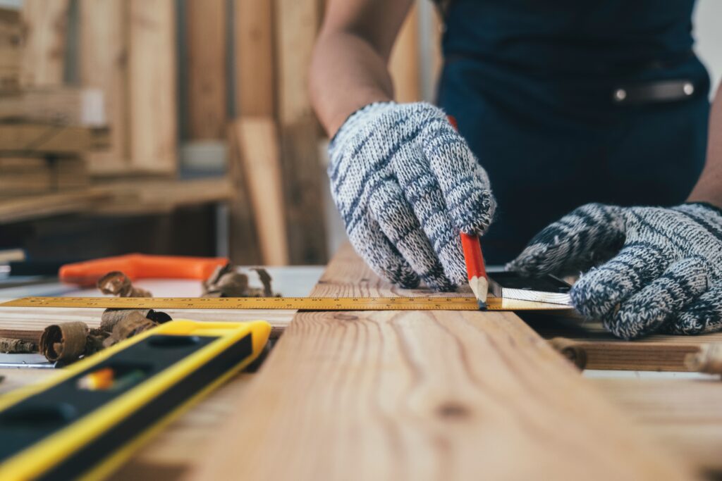 Carpenter working with equipment on wooden table in carpentry shop.