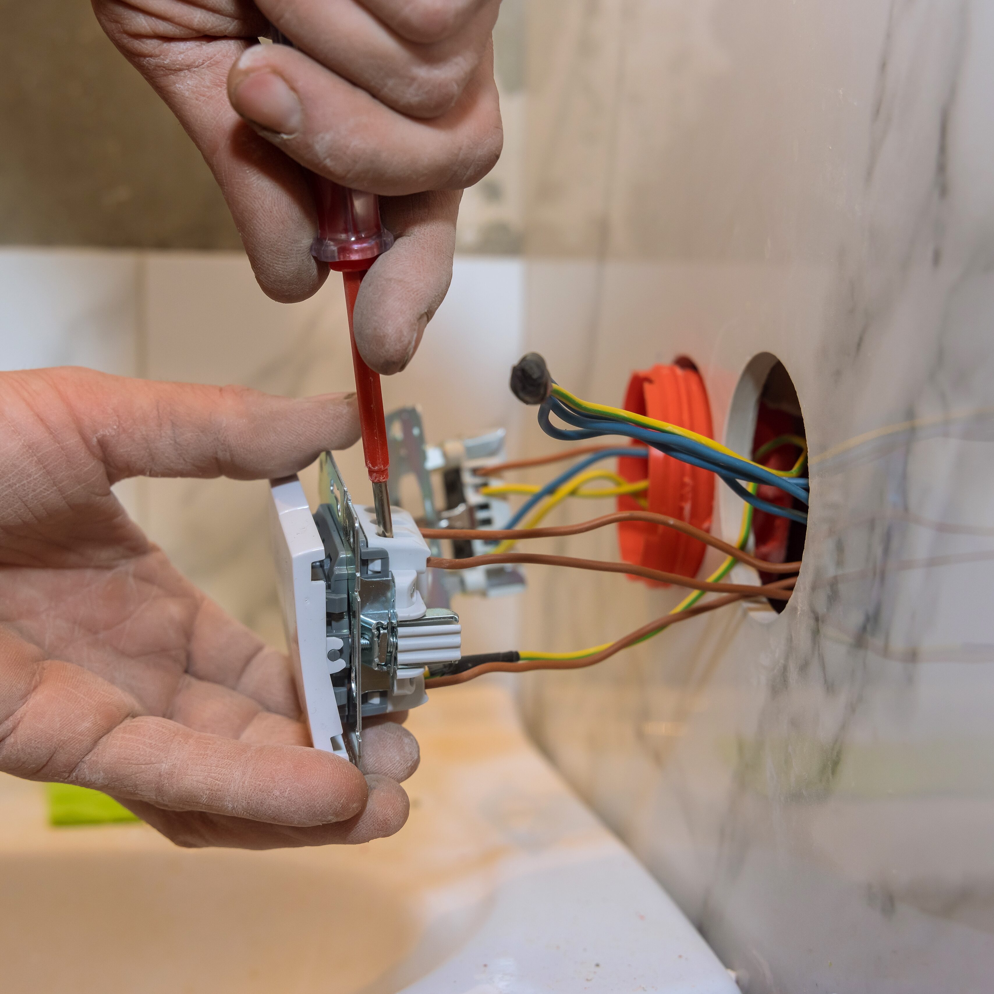 Electrician in mounting electric sockets on the wall